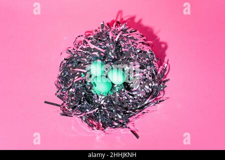 Over Head Shot Of Colourful Easter Eggs On pink Table placed as in a bird nest Stock Photo