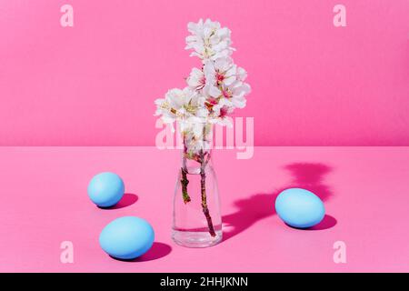 Almond blossoms in a transparent vase with water with three blue eggs Stock Photo