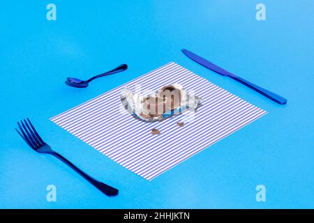 Broken chocolate egg on a plate on a blue background Stock Photo