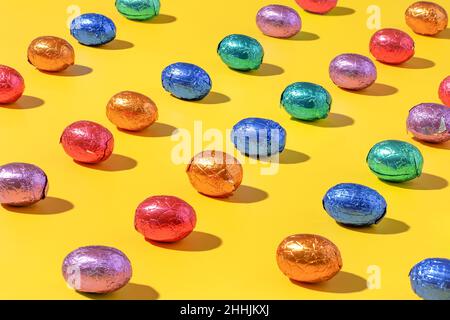 Pattern of colourful chocolate foil eggs on a yellow background Stock Photo