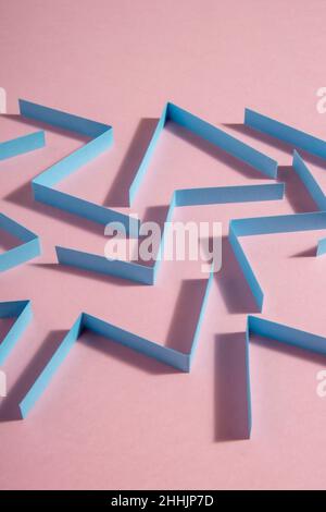 From above heap of abstract conceptual geometric paper zig zags patterns placed randomly on pink background in modern light studio Stock Photo