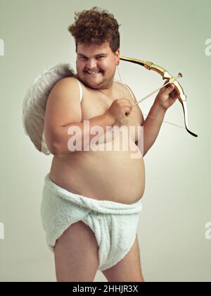 He's bringing the love this Valentine's. An obese man dressed as a cherub with a bow and arrow. Stock Photo