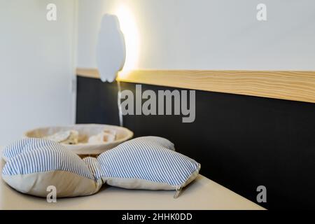 White baby booties and pants in rattan basket placed on white surface near black wall in light room at home Stock Photo