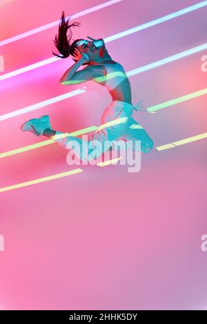 Side view of flexible female dancer in bodysuit lying on floor in studio and doing splits Stock Photo