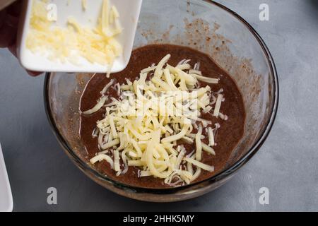 From above of crop anonymous cook adding grated butter into bowl with chocolate sweet waffle batter during cooking process in kitchen Stock Photo