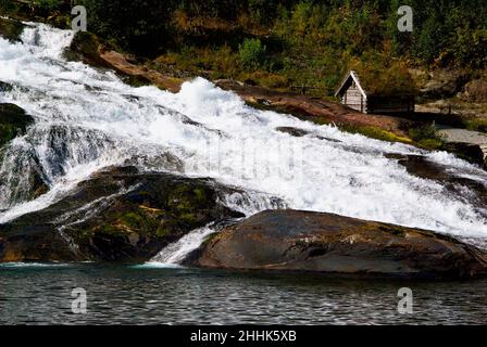 Hellesyltfossen rush down the mountain in front of a small cottage in the village Hellesylt in Møre og Romsdal fylke in Norway. Stock Photo