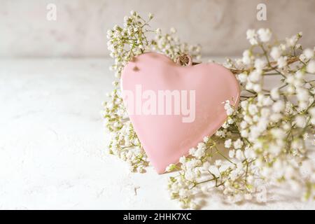 Rose colored heart shape and white gypsophila flowers on a light rustic background, love concept for valentines od mothers day, copy space, selected f Stock Photo