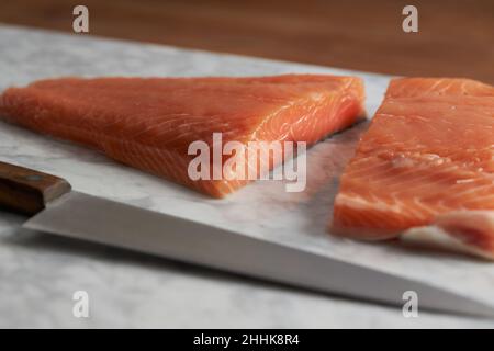 Top view of raw salmon fillet placed on cutting marble board on wooden table Stock Photo