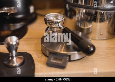 Portafilter for grinding coffee beans near tamper for making fresh espresso in coffee shop Stock Photo