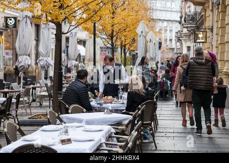 Picture of a white caucasian man, a waiter in uniform in belgrade, serbia, working and serving people while wearing a respiratory face mask during the Stock Photo