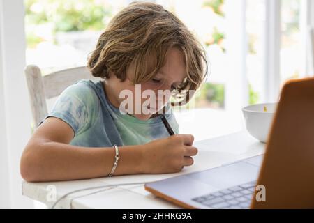 Boy (8-9) drawing picture during online lesson Stock Photo