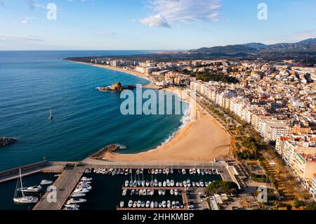 Drone view of coastal Spanish town of Blanes overlooking port, sandy beach and Sa Palomera Rock Stock Photo