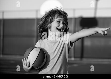 Happy smilin kid playing basketball, pointing showing gesture. Activity and sport for kids. Stock Photo