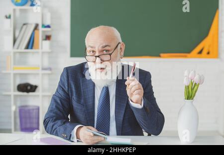 Teacher preparing for university exams. Professor holding a book and pointing. Teacher in college on university lecture. Stock Photo