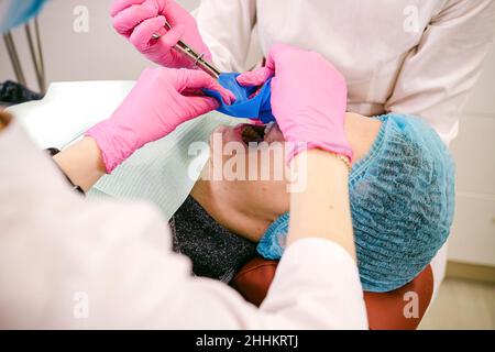 Patient man visiting dentist for regular check-up and dental filling by stomatologist an assistant in medical private clinic. Stock Photo