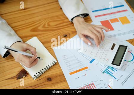 Cropped image of a female accountant, or financial investment consultant using calculator and taking notes on notepad. Stock Photo