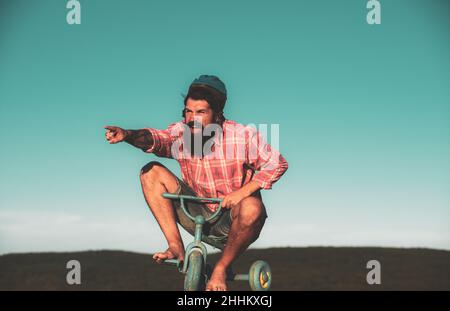 Funny man on a bicycle. Emotional crazy guy on a childrens bike. Stock Photo