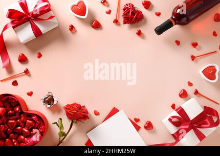Valentine's day greeting card with red wine, gift, hearts chocolate sweets and red roses on pink background. View from above. Space for your greetings Stock Photo