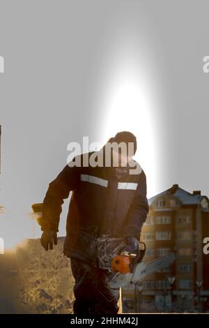 Worker with a chainsaw in hand at the assembly site of the ice town Stock Photo