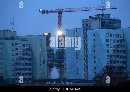 Magdeburg, Germany. 25th Jan, 2022. The morning dawns over the construction site of the replacement Strombrückzug, which can be seen behind high-rise residential buildings. The day remains cloudy and dry, as in previous days. Credit: Klaus-Dietmar Gabbert/dpa-Zentralbild/ZB/dpa/Alamy Live News Stock Photo
