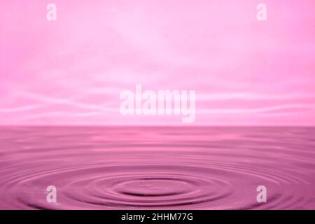 Bright pink background with diverging circles from dropped drop on surface water Stock Photo