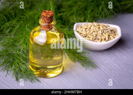 A bottle of fennel essential oil with fresh green fennel twigs and fennel seeds in the background Stock Photo