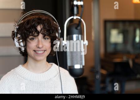 A young curly hair singer woman recording a song in a real studio Stock Photo