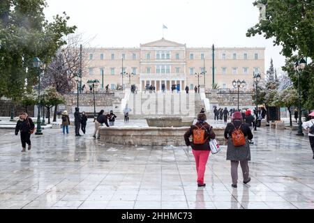 People in Athens, Greece, walking at Syntagma Square during a very cold winter day, with sleet falling and a snowstorm coming in January 24th 2022 Stock Photo