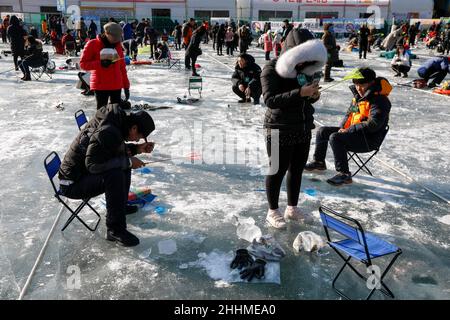 January 5, 2019-Hwacheon, South Korea-Visitors cast lines through holes drilled in the surface of a frozen river during a trout catching contest in Hwacheon, South Korea. The contest is part of an annual ice festival which draws over one million visitors every year. Stock Photo