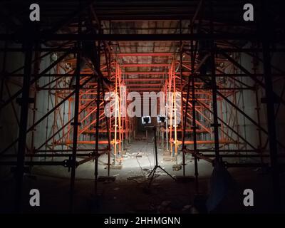 Interior of a bridge deck under construction supported by scaffolding, illuminated by spotlights. Construction site concept Stock Photo