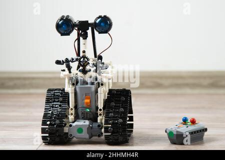 The robot from the children's designer on the control panel. DIY educational toy. A radio-controlled robot rides on the floor. Robotics in action. Robot from the constructor. Stock Photo