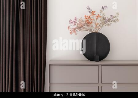 Dried colourful spring flowers in black hand glazed ceramic vase in nordic style against white wall. Minimal interior decoration concept Stock Photo