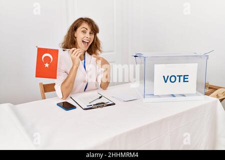 Beautiful caucasian woman at political campaign election holding tunisia flag smiling happy pointing with hand and finger Stock Photo