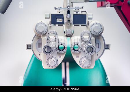 Optician's instrument for measuring sight. Eye test equipment. White Eye examination tool with a green ophthalmologist chair Stock Photo