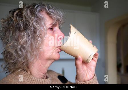 Woman drinking coffee from a recyclable paper butterfly cup Stock Photo