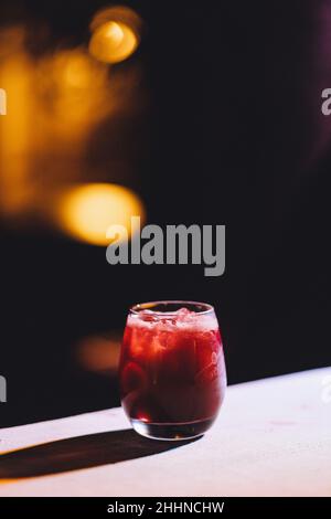 A vertical shallow focus shot of a red drink in a glassy cup on a table Stock Photo