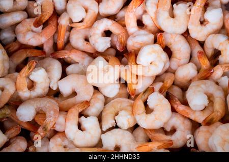 Close-up of a pile of frozen orange shrimps. Peeled shrimp with tails only. Natural seafood background. Stock Photo