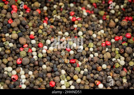 Black, White, Red, and Green Kampot and Madagascar Peppers mixed as Background. Stock Photo