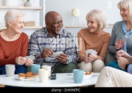 Senior friends playing cards while drinking tea at home Stock Photo