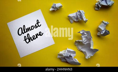 Top view of almost there text on notepad with trash papers and yellow background. Motivational concept. Stock Photo