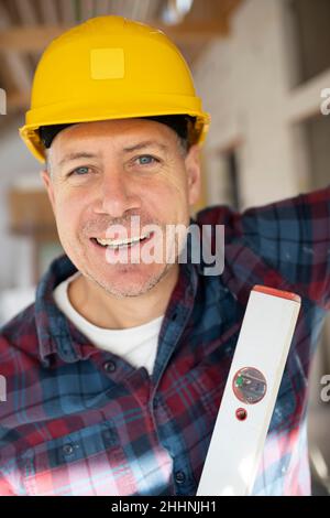 Portrait of construction worker on building site with yellow safety helmet and checkered shirt in an interior room or loft Stock Photo