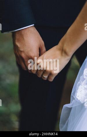 Vertical shot of the bride and groom holding hands with weddings rings Stock Photo