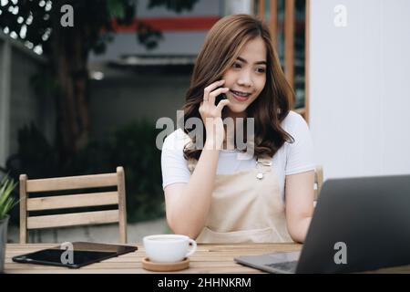 Young Asian student talking with friend by mobile phone outdoor park. Stock Photo