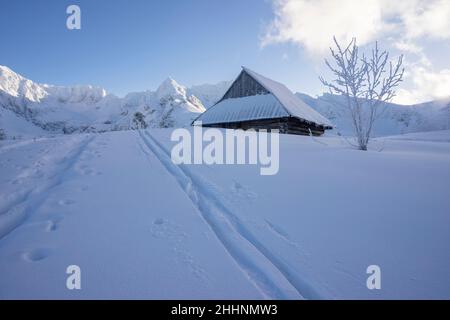 An old hut in a winter landscape with peaks in the background. Gasienicowa Valley. Tatra Mountains. Stock Photo