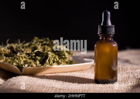 Cannabis oil extract in droplet bottles. Dried hemp leaves and seeds in background Cbd oil from medical marijuana. Copu space. Stock Photo