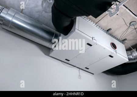modern heat recovery ventilation system mounted on ceiling in house service room. recuperator Stock Photo