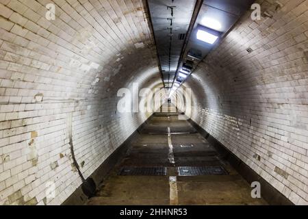 Looking down a narrow Foot Tunnel with people walking in the far distance, taken at Greenwich Foot Tunnel under the River Thames, 30th December 2022 Stock Photo