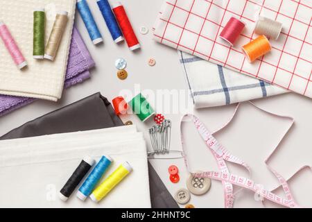 Fabric and threads on a gray background.Sewing tools and accessories. Stock Photo