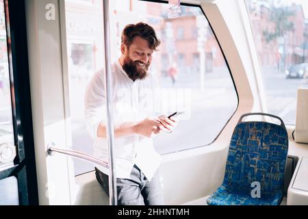 Bearded man using phone in bus Stock Photo