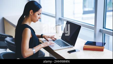 Serious female entrepreneur working on netbook in workspace Stock Photo